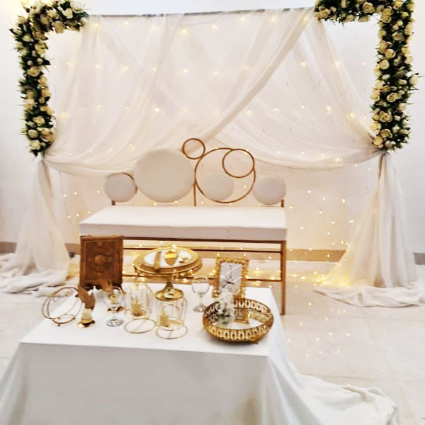 White Shade Wedding Decoration with Big Table, 1 White Couch, Gate Square Metallic Stand Decorated with Flowers & Sheet, Golden Metallic Quran Book, etc..